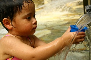 photo of young girl getting a drink from a fountain